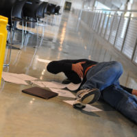 A man who slipped on a wet floor beside a bright yellow caution sign holds his back in pain A man who slipped on a wet floor beside a bright yellow caution sign holds his back in pain