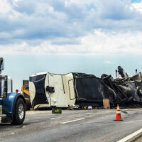 Fifth wheel RV overturned on highway with wench truck trying to get it off the road and two semis parked nearby and traffic cones keeping traffic away Fifth wheel RV overturned on highway with wench truck trying to get it off the road and two semis parked nearby and traffic cones keeping traffic away